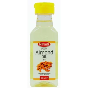 A clear glass bottle filled with light yellow almond oil, with a white label featuring the Niharti brand name