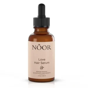 A 50ml glass bottle of Noor Hair Essence Oil with a black label and dropper cap