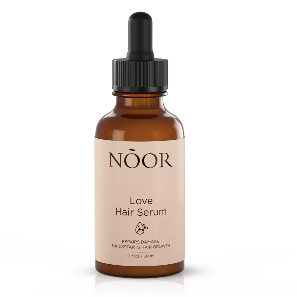 A 50ml glass bottle of Noor Hair Essence Oil with a black label and dropper cap
