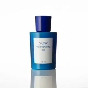 A clear glass bottle with a white label containing NOW Foods Moisturizing Jojoba Oil. The bottle has a black screw-top lid.