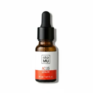 A clear glass bottle containing a light yellow facial serum. The bottle has a white label with the Atomu brand name and product details.