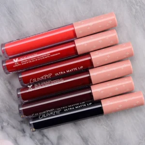 A small, cylindrical tube of Colourpop Ultra Matte Lip Stain in a matte black color with the Colourpop logo on the label