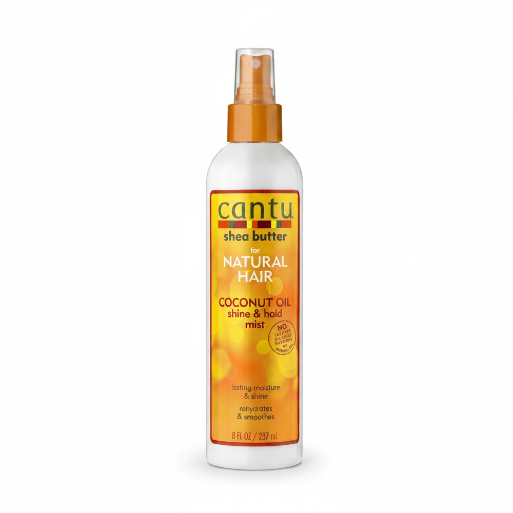 A bottle of Cantu Shea Butter Coconut Oil Shine & Hold Mist. The bottle is white with a green label and cap, and the product name is displayed prominently.